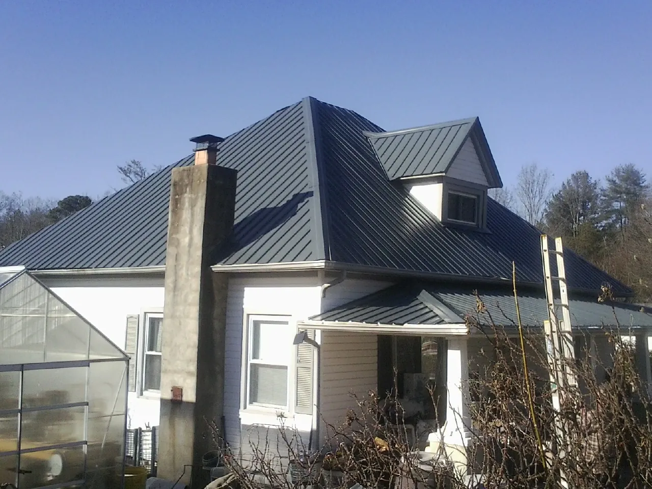 Dark blue standing seam metal roof on a white farmhouse with dormer — Slate & Tile Roof Repair by Roofing Brothers in Letart