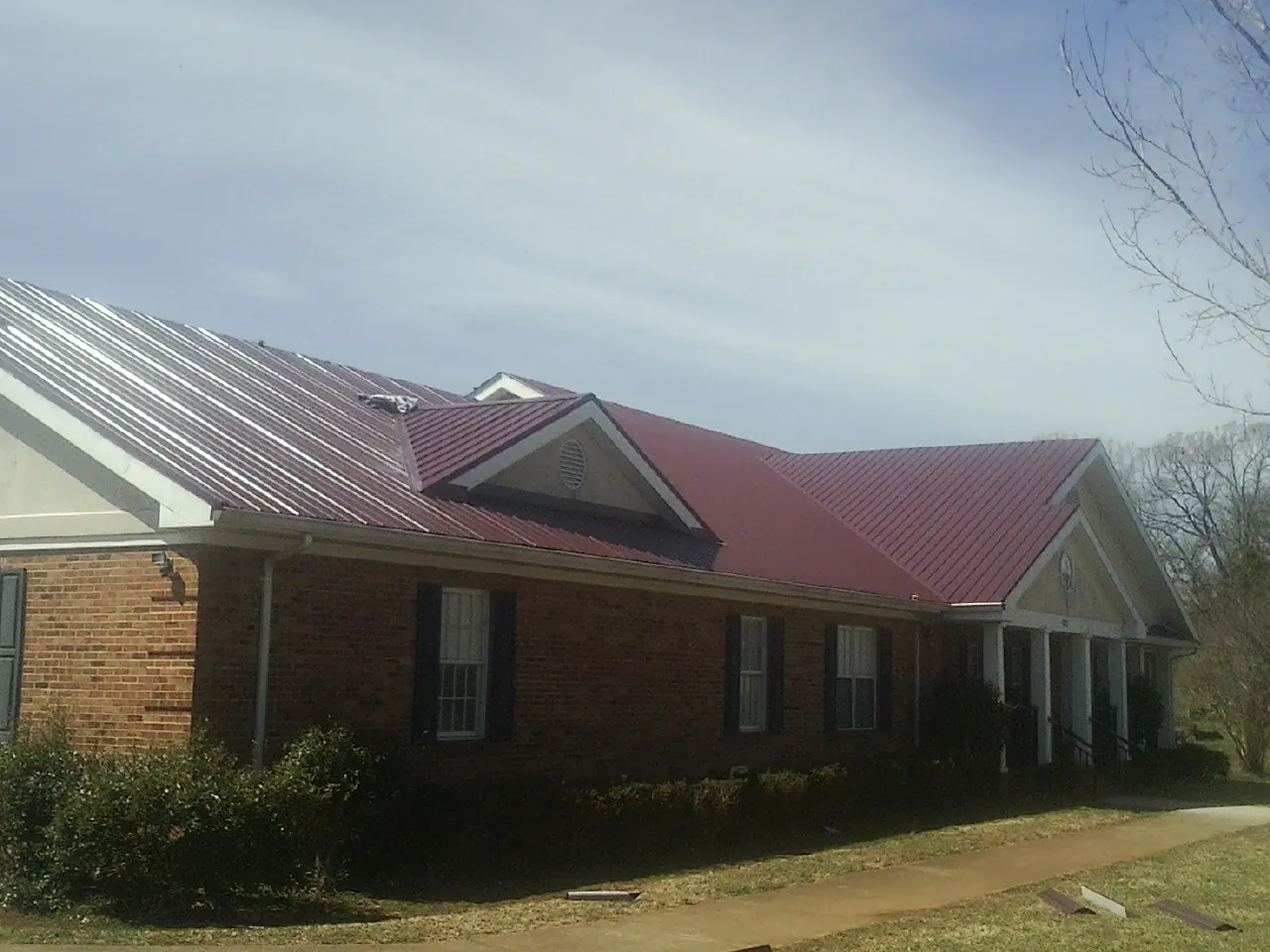 Red metal roof with gabled entries on a long brick building in Letart