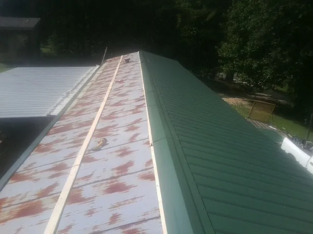 Old rusted panels beside newly installed green metal roofing — Wind Damage Roof Repair by Roofing Brothers in Letart