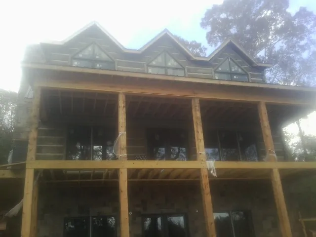 Dormers and porch framing on a large log home under construction — Roof Coating work by our crew in Letart