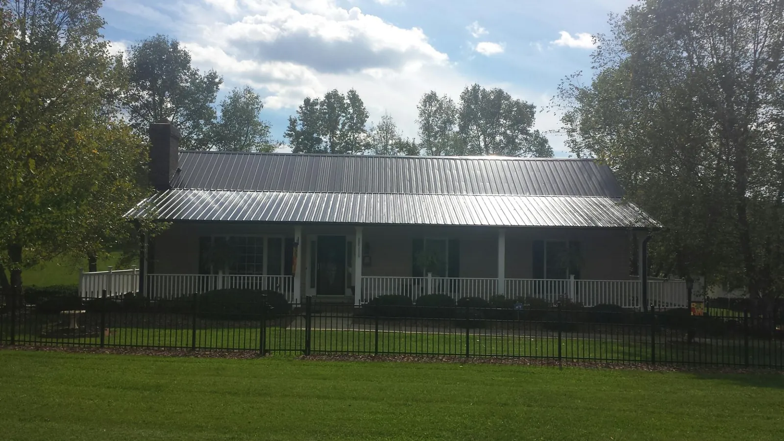 Gray metal roof on a brick ranch with a full width front porch — Gutter Guard Installation work by our crew in Letart