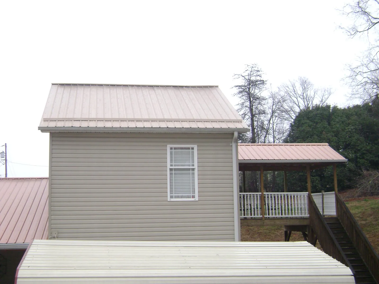 Tan metal roofs on a two story addition and attached porch, from a Roof Replacement job in Letart