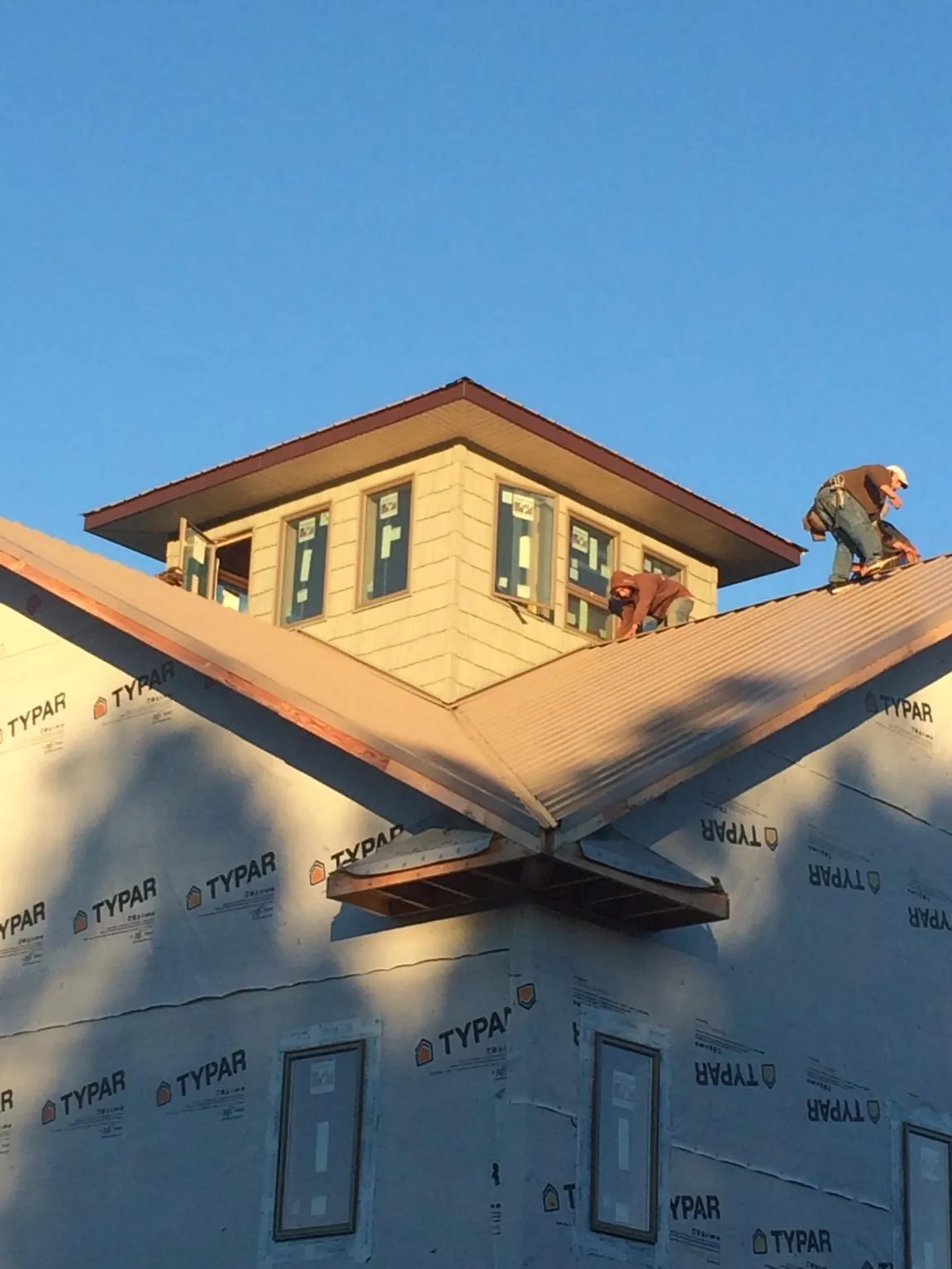 Roofers working around a rooftop cupola on a new metal roof at sunset — Roof Waterproofing in Letart by Roofing Brothers
